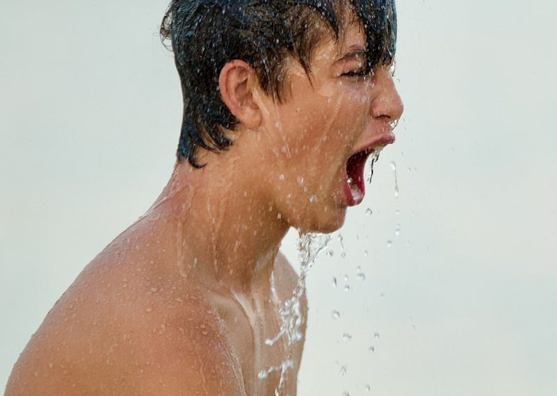 topless man with water droplets on his face